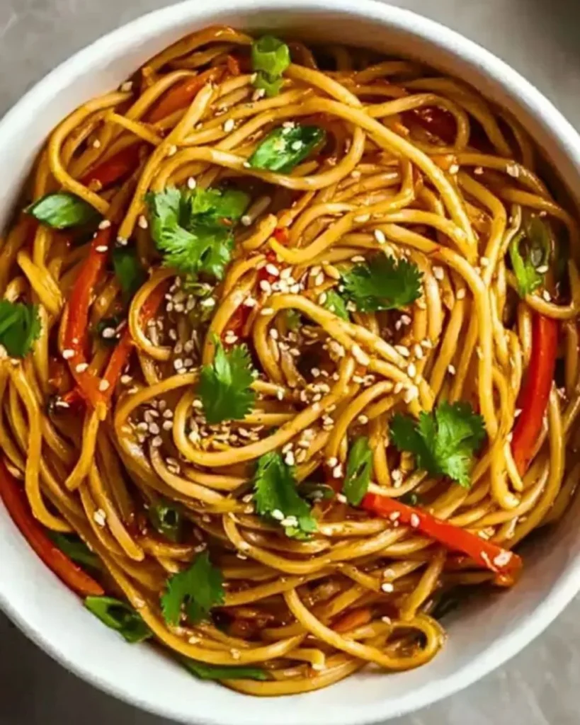 Delicious Asian Sesame Noodles topped with fresh vegetables and sesame seeds.