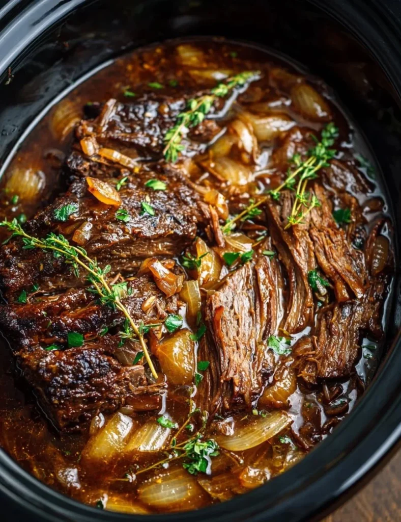 Delicious French Onion Pot Roast served on a plate with herbs.