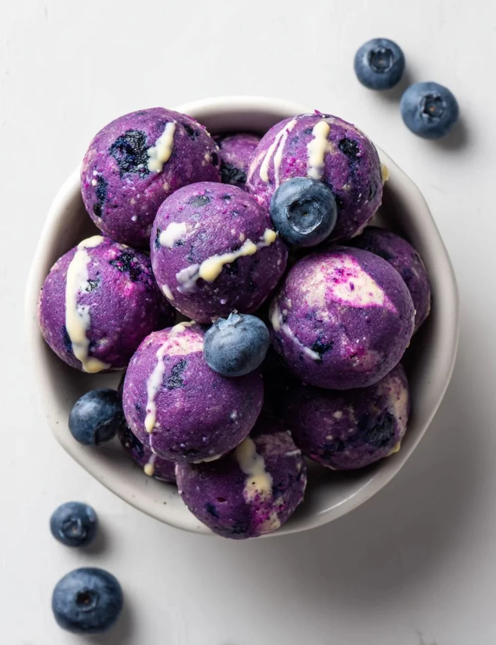 Blueberry Cheesecake Protein Bites on a white plate with blueberries