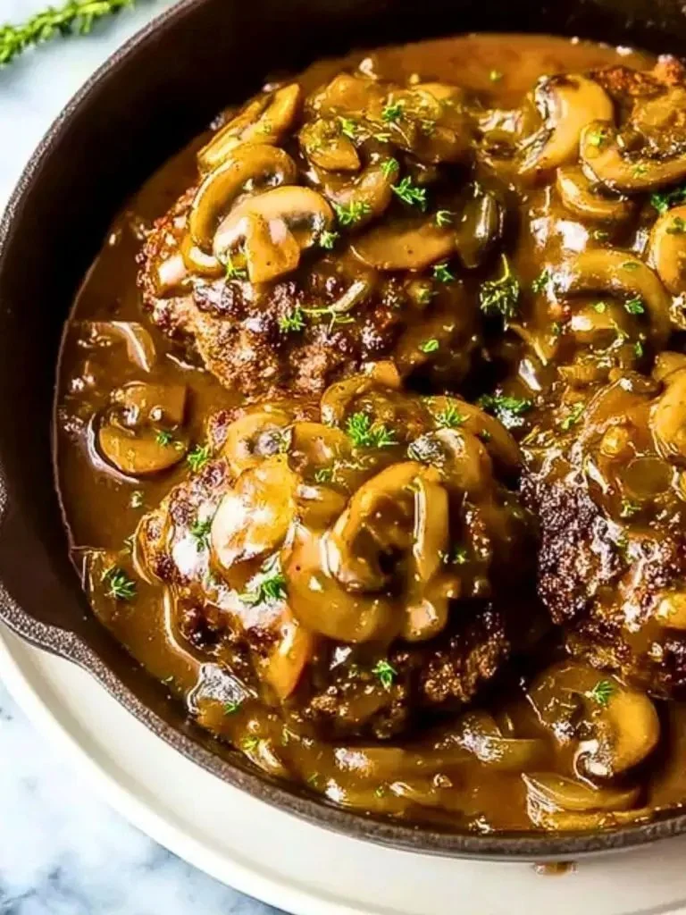 Homemade Salisbury steak served with gravy and vegetables on a plate.