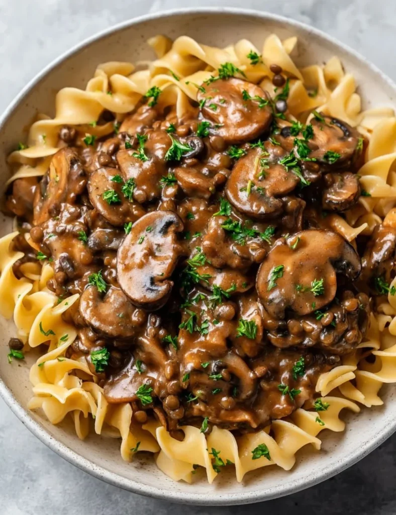 Delicious bowl of Lentil Mushroom Stroganoff topped with herbs and served with pasta.