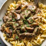 Delicious quick simple beef stroganoff served with pasta and garnished