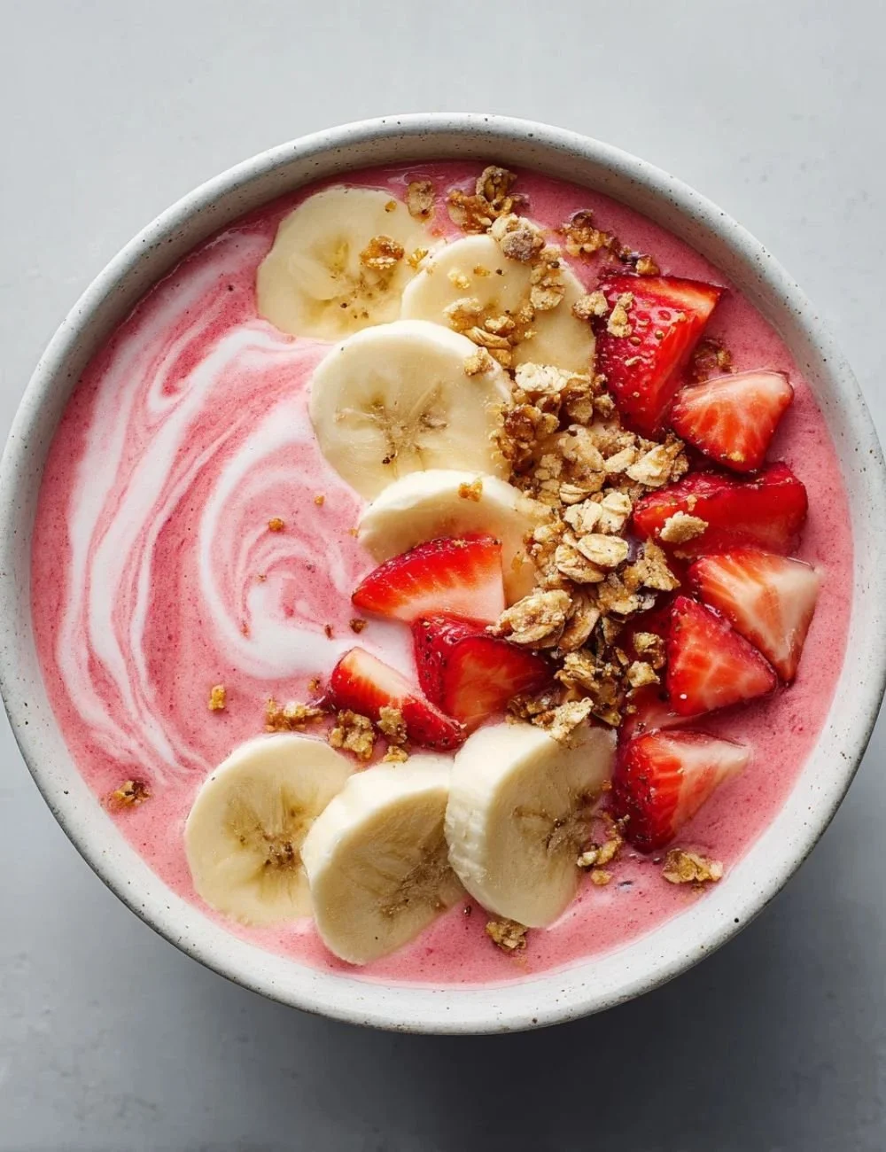Delicious strawberry banana smoothie bowl topped with fresh fruits and granola