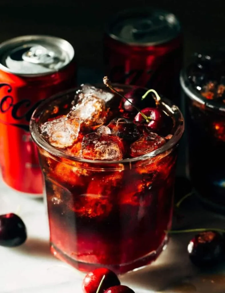 Delicious Cherry Coke Margarita in a glass garnished with cherries and lime.