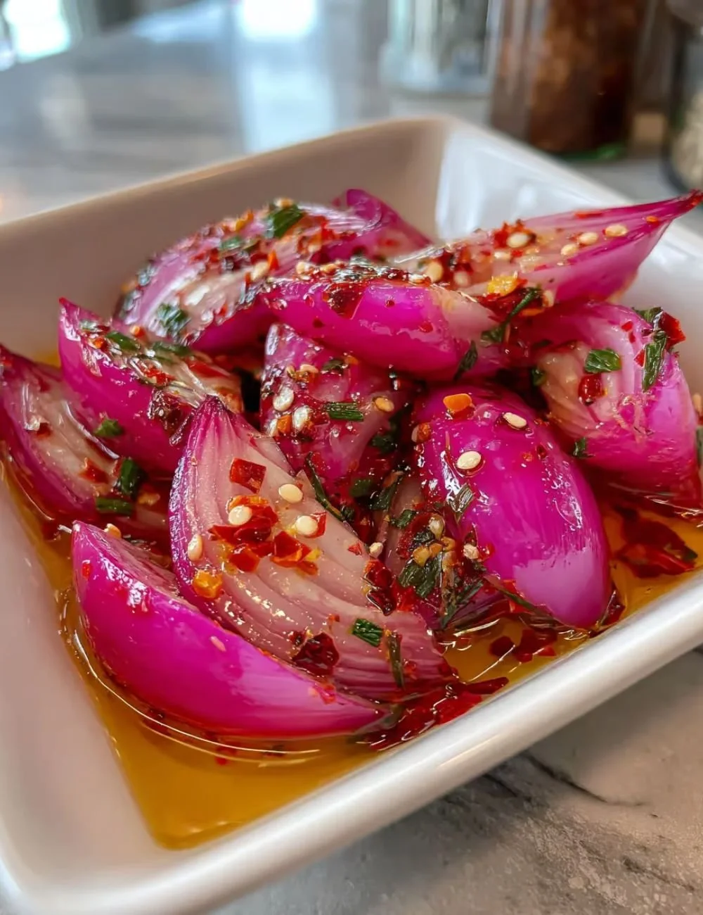Jars of hot honey pickled red onions on a wooden table.