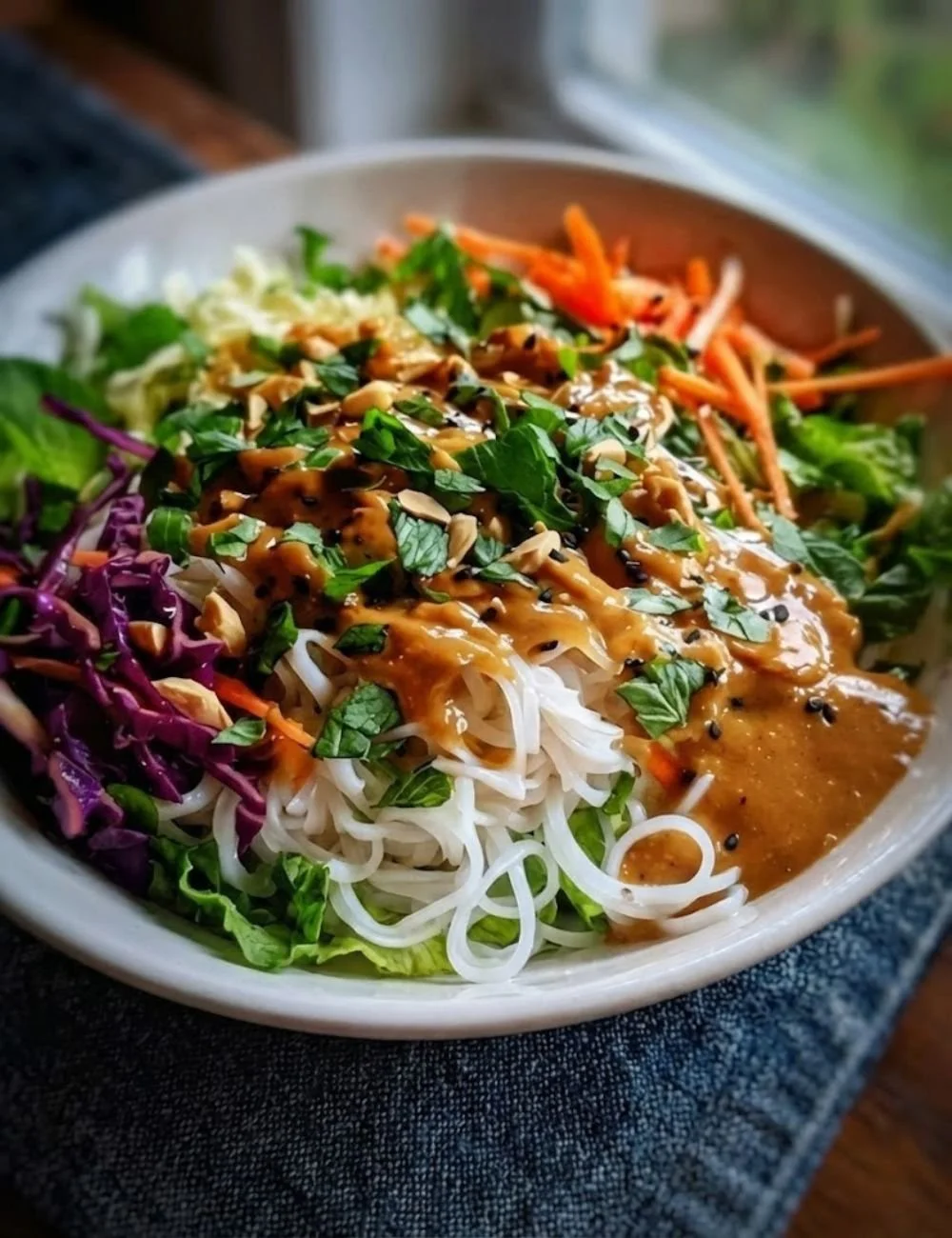 Delicious spring roll salad topped with creamy peanut dressing served in a bowl.