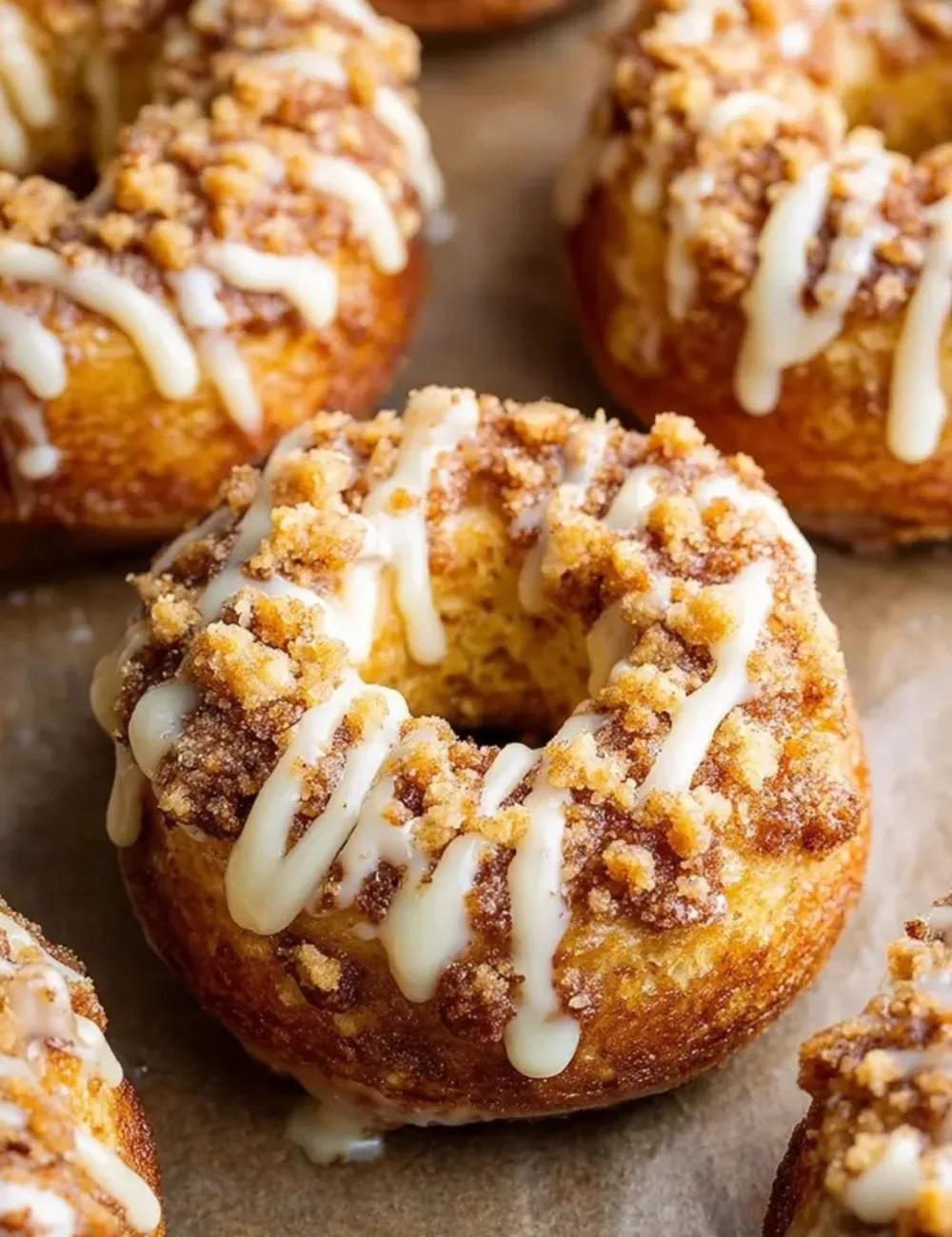 Baked coffee cake donuts drizzled with vanilla glaze on a wooden table