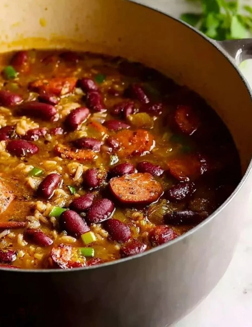 Bowl of simple red beans and rice dish garnished with herbs on a wooden table.