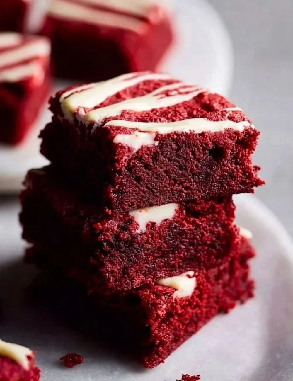 Fudgy red velvet brownies topped with cream cheese frosting on a wooden table