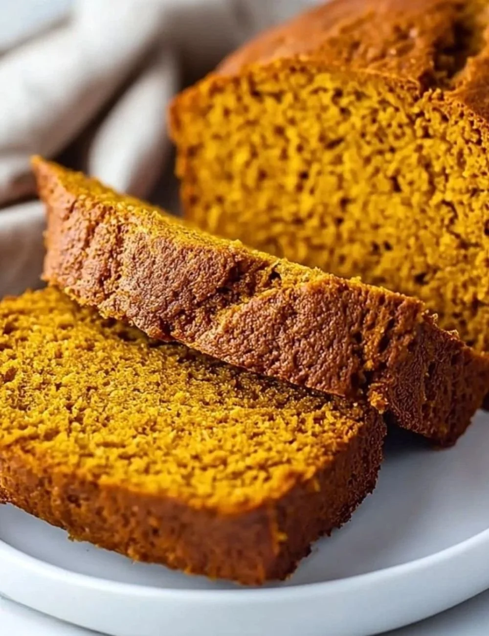 Slice of ultra-moist vanilla pudding pumpkin bread on a wooden table